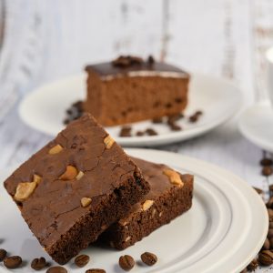 chocolate brownies on a white plate and coffee beans.