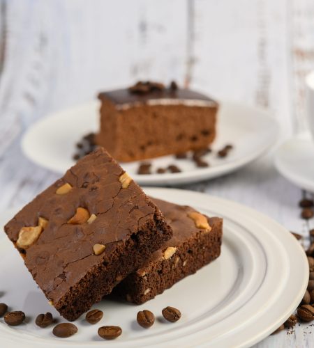 chocolate brownies on a white plate and coffee beans.